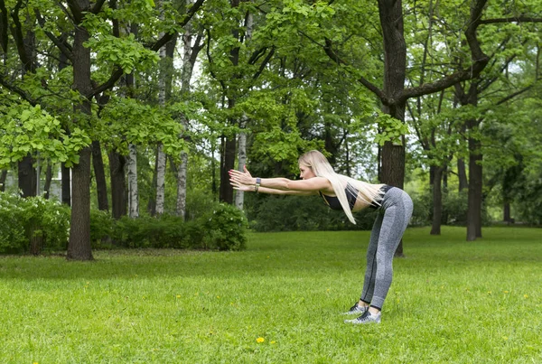 Струнка дівчина спорту в парку, вона робить вперед вигини — стокове фото