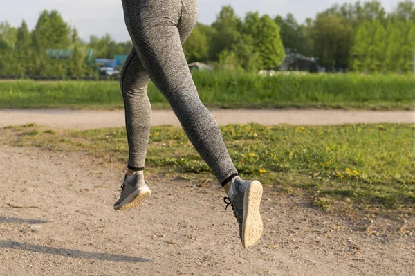 Mädchen läuft im Park, Frauenfüße in grauen Leggings und Turnschuhen — Stockfoto