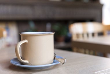 kaf masada bir tabak üzerinde bir kaşık ile bej metal kupa