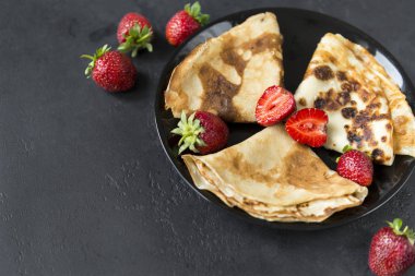 siyah bir backgroun üzerinde siyah bir tabak üzerinde çilek ile krep