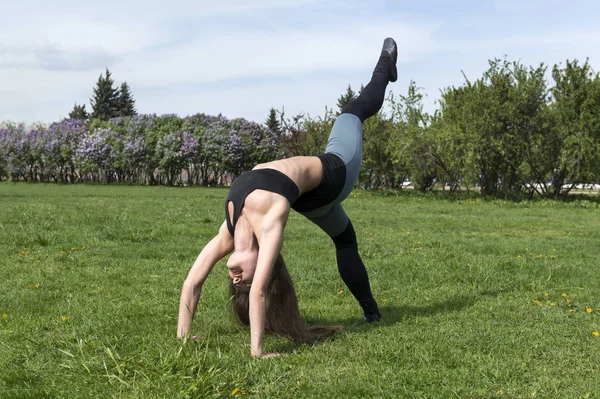 Mädchen macht Brücke mit erhobenem Bein, Mädchen in Sportkleidung tut — Stockfoto