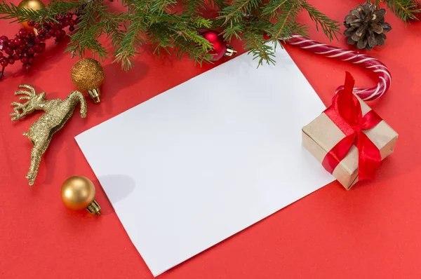 blank sheet of paper on a red background, a gift, a fir branch,