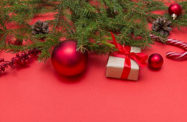 kırmızı bir arka plan üzerinde taze ladin dalı, kırmızı topları, şeker, hediye 