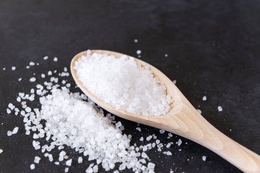 siyah yüzeyde kaşık ve rassypany tuz, kaba deniz sal