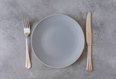 1 boş gri plaka, çatal, gri beton arka plan üzerinde bıçak, üst