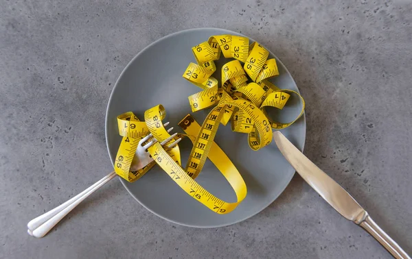 Yellow measuring tape on a gray plate on a gray background, — Stock Photo, Image