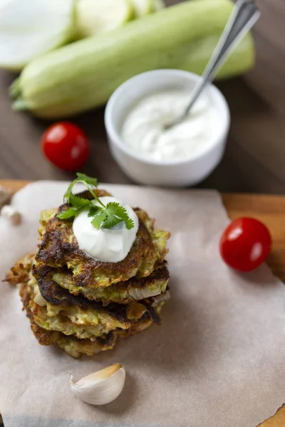 zucchini pancakes with sour cream and herbs on a Board