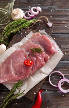 Koyu ahşap zemin üzerinde bitkiler, baharatlı domuz filetosu, biberiye, biber biber, soğan, tuz, mantar., 