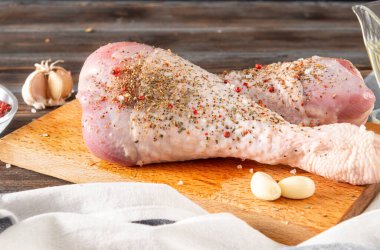 Mutfakta 2 çiğ hindi bacağı var. Baharat, sarımsak, kahverengi ahşap arka planda havlu., 