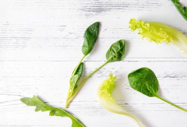 Otlar, yeşil marul, ıspanak, beyaz ahşap arka planda roka yaprakları., 