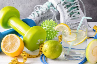 Dambıllar, limonlu bir bardak su, mezura, ip atlama, top, spor ayakkabısı, kireç, beyaz arka plan