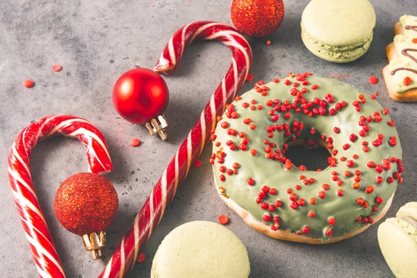 red lollipops, donuts, cookies, green macaroons, red Christmas balls on a gray background, Christmas sweets