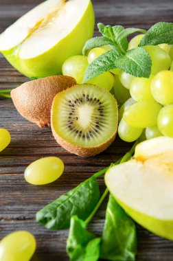 Taze yeşil kivi yarımları, üzümler, elma, ahşap arkaplanda nane., 