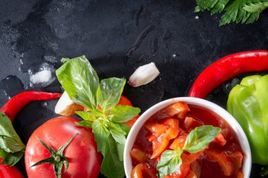 yeşil fesleğenli taze Lecho, domates dilimleri, kırmızı biber, sarımsak, buz küpleri, siyah arka planda, sos üstü görünümü,