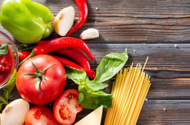Taze domates, çiğ makarna, fesleğen, kırmızı biber, sarımsak, soğan kahverengi ahşap arka plan manzaralı tatlı yeşil biber.