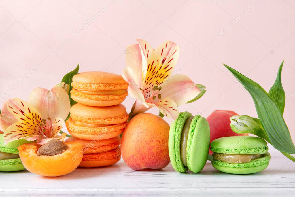 peach, green macaroon cookies , yellow Alstroemeria flowers, fresh apricots on a beige background