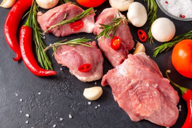 Sarımsaklı, biberiyeli, mantarlı, domatesli ve kırmızı biberli, siyah arkaplanlı, domuz etli ve sebzeli çiğ et.