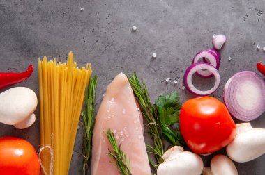 çiğ tavuk fileto, spagetti, makarna, et, sebze, otlar, domates, soğan, biberiye, biber, biber, yumurta, salatalık, gri arka planda mantar