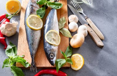 Baharatlı ve limon dilimli 2 çiğ uskumru balığı, biber, mantar, bıçak, çatal, fesleğen, sarımsak, soğan. 