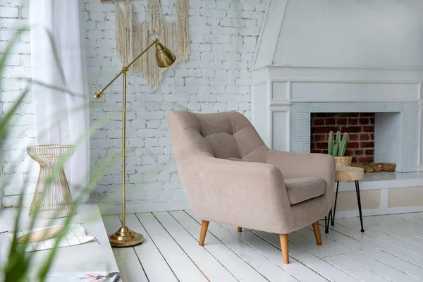 beige armchair in a bright room near the window, white fireplace