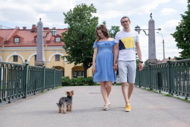 Beyaz adam sokakta yürür hamile beyaz bir kadın ve bir köpekle, ailesi yürüyüşe çıkar.