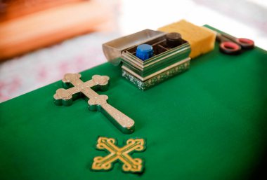 Hıristiyan haçı, Ortodoks Kilisesi 'nde yeşil masa örtüsü olan bir masada kavanoz yağ.