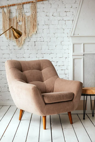 Pencerenin yanındaki bir ışık odasında, beyaz bir duvara, şömineye yaslanmış kahverengi sandalye.