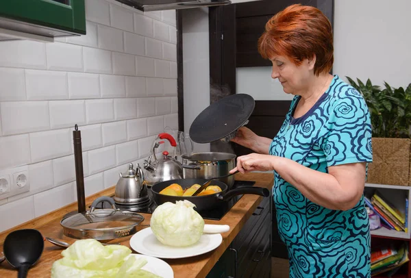 Mutfakta 1 yetişkin kadın dolma biber ve lahana hazırlıyor.