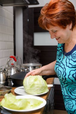 1 beyaz kadın. 60 yaşında. Mutfakta yemek pişiriyor.