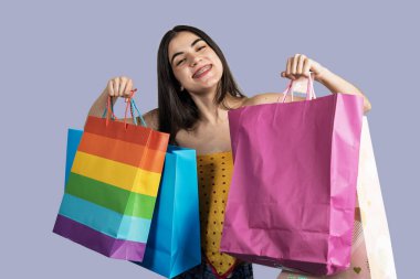 Mutlu müşteri alışveriş torbalarını gökkuşağı renginde gösteriyor, gülümsüyor ve lgbtq + gururunu kutluyor.