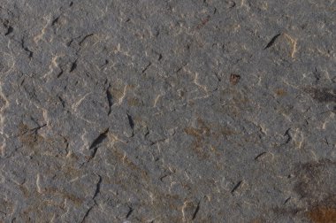 Güneş ışığıyla yıkanmış doğal taş dokusunun yüksek kaliteli görüntüsü. Fotoğrafta taşlar doğal desenler, renkler ve pürüzsüzlük, doğa fotoğrafçılığı, manzara tasarımı, çevre projeleri ve arka plan dokuları için mükemmel..