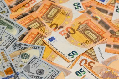 Masaya saçılmış 100 ABD doları banknotları ve 50 avroluk banknotların Macro görünümü, mali ve ekonomik kullanım için dokulu bir para arka planı oluşturur.