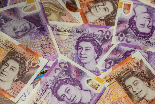 Крупный план британских банкнот весом 20 фунтов с портретами короля Карла III и королевы Елизаветы II, символа переходной валюты и монархии Великобритании.