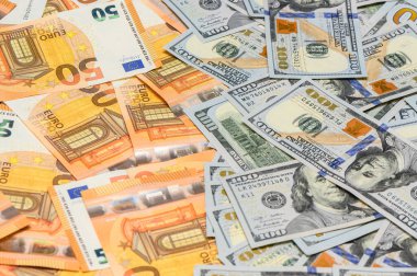 Servet, finans ve uluslararası parayı temsil eden dağınık yüz Amerikan doları ve elli avroluk banknotların yakın plan çekimi.