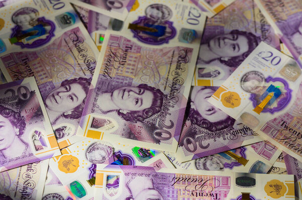 Несколько 20 банкнот Соединенного Королевства разбросаны в виде текстурированного денежного фона, представляющего финансовый, деловой и экономический рост.