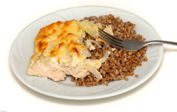 Hearty and wholesome dish of baked meat served with buckwheat porridge on a white plate.