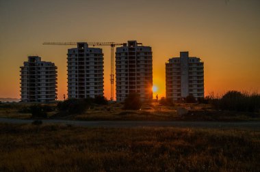 Kıbrıs 'ın Akdeniz kıyısında batan güneşin yumuşak parıltısıyla aydınlanan modern bir yerleşim tesisi inşa ediliyor..