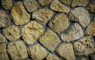 Güneş ışınları desenli yüzeyde desenler oluşturan bir taş cephenin yakın çekimi. Tasarım ve fotoğrafçılık için mükemmel bir kırsal arkaplan.