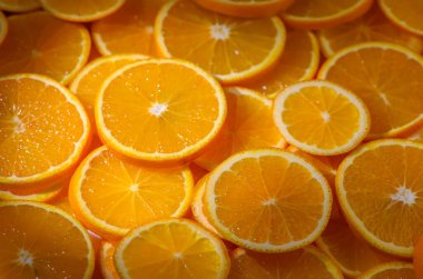 Taze portakal dilimleri bir masaya yerleştirilmiş halkalara kesilir. Canlı renkler ve sulu dokular yemek fotoğrafçılığı için parlak ve doğal bir zemin oluşturur..