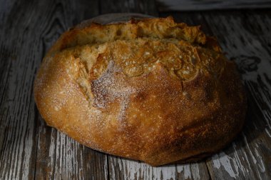 Tahta yüzeyinde altın kabuklu ev yapımı tam buğday ekmeği. Kırsal ve doğal sunum yemek fotoğrafçılığı ve mutfak içeriği için mükemmel.