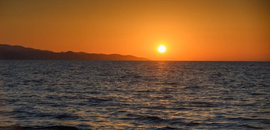 Kıbrıs, Morphou Körfezi 'nde güzel bir gün batımı. Akdeniz 'i yansıtan akşam gökyüzünün ılık renkleri. Yaz tatilleri için manzaralı kıyı manzarası.