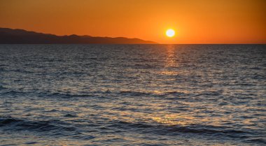 Kıbrıs 'ın Morphou Körfezi' nde akşam batımı. Sakin Akdeniz kıyısında, sakin atmosferi ve güzel doğal manzarası olan altın bir ışık..
