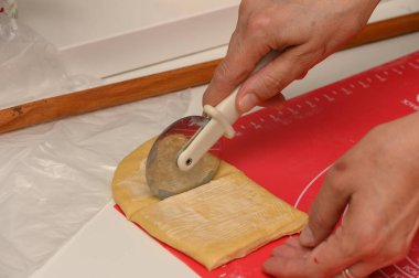 Kadın, ev mutfağında Parker House çörekleri için yumuşak hamuru parçalara ayırıyor..