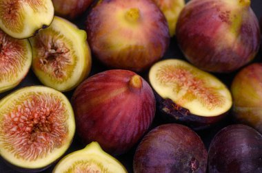 Olgun, sulu mor incirlerin yakın çekimi, canlı ve dokulu bir arka plan yaratarak yiyecek, tropikal ve doğa temalı stok fotoğrafçılığı için idealdir. Doğal arka plan olarak sulu mor incirler. Yüksek kalite fotoğraf