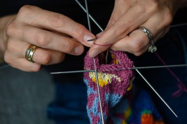 Karmaşık desenli bir çorabın ayrıntılı örgüsü. Sanatsal el işi, çalışmanın yakın çekimi devam ediyor.