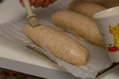 Bir kadın, Graham somunlarını fırına koymadan önce yumurta yıkama makinesiyle nazikçe fırçalar..