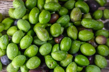 Kıbrıs 'ta toplanan taze yeşil zeytinler kırsal ahşap masaya yerleştirildi. Geleneksel Akdeniz gıda sembolü, mutfak, tarım ve organik yaşam tarzı kavramları için mükemmel. Tahta Masa 'da yatan Kıbrıs zeytinleri. Yüksek kalite fotoğraf