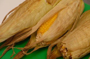 Fırında pişirilmiş taze mısır koçanları, doğal aromalı sıcak servis edilir..