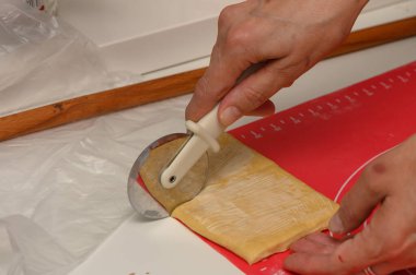 Bir kadın ev yapımı Parker House dürümleri hazırlıyor, rahat bir mutfak ortamında yumuşak hamur dilimliyor..