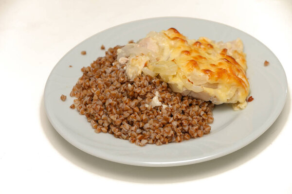 Buckwheat porridge with roasted meat on white background